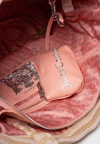 Rosa tygkasse inuti med en dragkedja ficka, med ett upprepande logomönster och silverdetaljer. Slät textur hela vägen igenom.