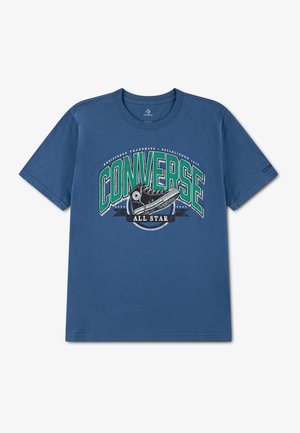 Blå T-shirt med korte ærmer med grønt og hvidt Converse All Star-logo og en sort høj top sneaker grafik på foran i midten.