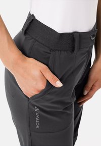 Svarta, lätta byxor med en texturerad elastisk midjeband, sidfickor och en synlig varumärkeslogotyp. Har en skräddarsydd passform och slät tyg.