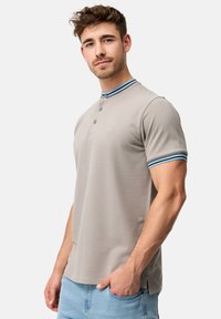 Polo shirt Henley in grigio chiaro, con colletto a righe blu e bianche, chiusura a tre bottoni e maniche corte. Texture morbida.