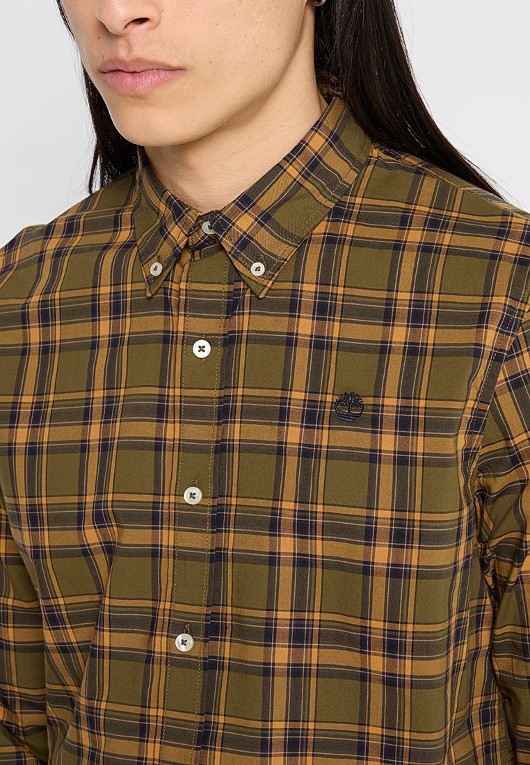 Camicia a quadri verde e gialla con colletto abbottonato, dotata di bottoni bianchi e un piccolo logo ricamato sul petto.