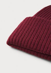 Red ribbed knit beanie with a thick cuff, featuring a soft texture and a snug fit, suitable for cold weather conditions.