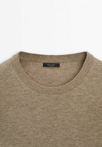 Pull beige à col rond avec col côtelé et une étiquette intérieure noire indiquant "Massimo Dutti Made in China".