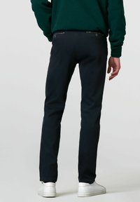Marineblauwe broek met een rechte pasvorm, voorzien van een gestructureerde tailleband, twee achterzakken met knoopsluitingen en een lichte toelopende broekspijp bij de enkels.
