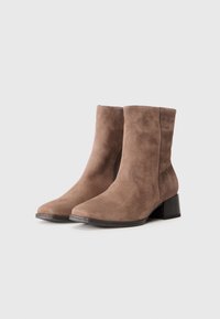 Botine din suede maro, cu vârf pătrat, fermoar lateral și toc bloc, având o textură netedă și un design minimalist.