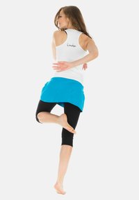 Sportoutfit mit einem weißen ärmellosen Oberteil, einem türkisfarbenen Rock und schwarzen Leggings. Das Oberteil hat ein Logo auf der Rückseite und einen taillierten Schnitt.
