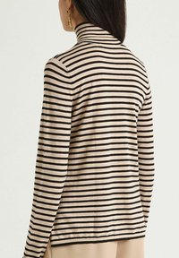 Langärmliges Rollkragenoberteil in Beige mit schwarzen horizontalen Streifen. Weicher Stoff, schlanke Passform und gerippter Kragen. Einfaches Design ohne Muster.