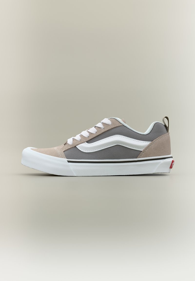 Κάτω αθλητικό παπούτσι με γκρι καμβά, μπεζ σουέντ λεπτομέρειες, λευκή γόμα στη σόλα, λευκά κορδόνια και λευκή πλευρική ρίγα σε ουδέτερο φόντο.