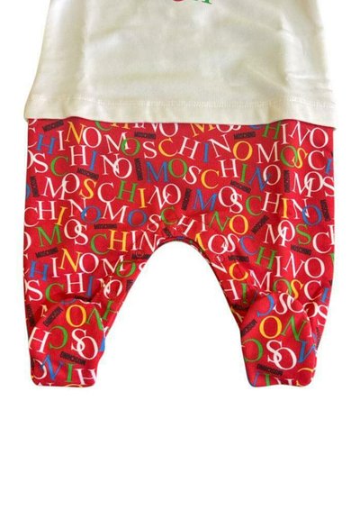 Czerwone spodnie dla malucha z wzorem kolorowego napisu „MOSCHINO”. Materiał jest miękki, spodnie mają luźny krój i zaokrąglone nogawki.