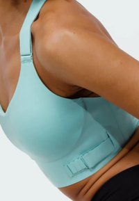 Sujeción deportiva azul claro con tirantes gruesos, escote en forma de V y cierre lateral de gancho y ojo. Tejido suave con costuras mínimas y un diseño ajustado.