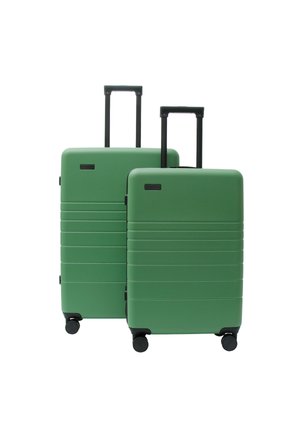 Zwei grüne Hartschalenkoffer mit ausgezogenen schwarzen Teleskopgriffen und vier schwarzen Rollen, auf weißem Hintergrund dargestellt.