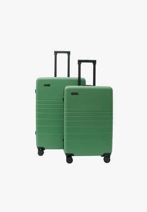 Zwei grüne Hartschalenkoffer mit ausgezogenen schwarzen Teleskopgriffen und vier schwarzen Rollen, auf weißem Hintergrund dargestellt.