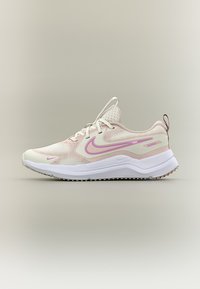 Ανοιχτό ροζ και μπεζ αθλητικό παπούτσι με λευκή σόλα και ροζ λογότυπο Nike, παρουσιασμένο σε ουδέτερο φόντο.