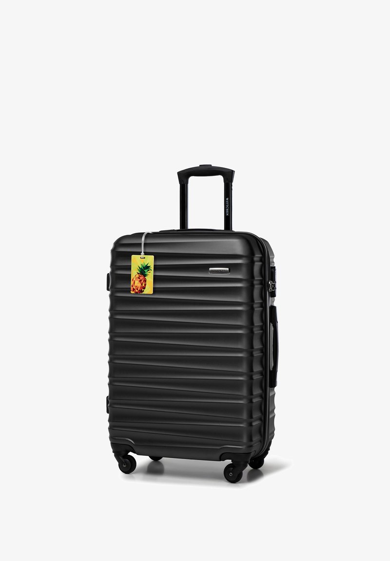 Černý tvrdý kufr s vertikálními rýhami, výsuvnou rukojetí a čtyřmi koly. Součástí je žlutá visačka s designem ananasu.
