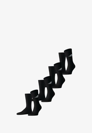 Schwarze Socken mit geripptem Bund, glatter Textur und einem Logodetail an der Seite. In einer Farbverlauf-Anordnung dargestellt.