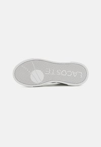 Fehér sneaker talp, amely texturált méhsejt mintázattal és kör mintázattal rendelkezik. A középtalpon lévő "Lacoste" logó többlet márkamegjelenítést biztosít.