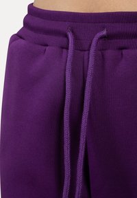 Lilla sweatpants med blød tekstur, elastisk talje og justerbare snore med en fletdesign.