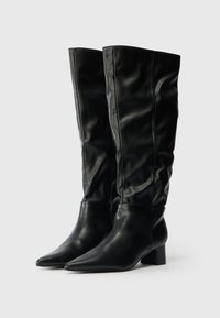 Cizme negre până la genunchi, realizate din piele netedă, cu vârf ascuțit și un toc bloc mic, având detalii pliate pe țeavă.