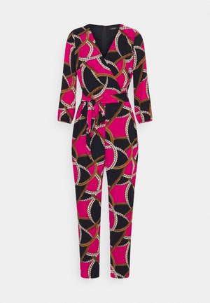 Combinaison rose à manches longues avec motif chaîne en noir, blanc et or, devant croisé et ceinture nouée à la taille.