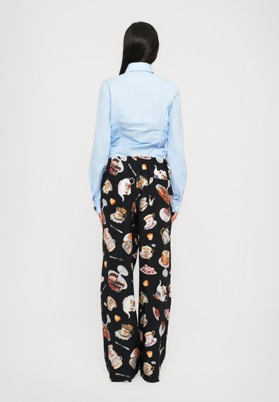 Cămașă cu mânecă lungă de culoare albastră deschisă, cu guler, asortată cu pantaloni negri care au imprimeuri colorate cu alimente și cescute de ceai. Materiale netede, croială lejeră.
