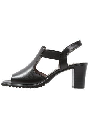 Sandale en cuir noire à bout ouvert avec panneaux élastiques sur les côtés, bride au talon et talon bloc sur fond blanc.