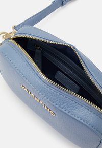 Blue textured leather purse with gold zipper and branded detailing; features dual compartments and a detachable strap.