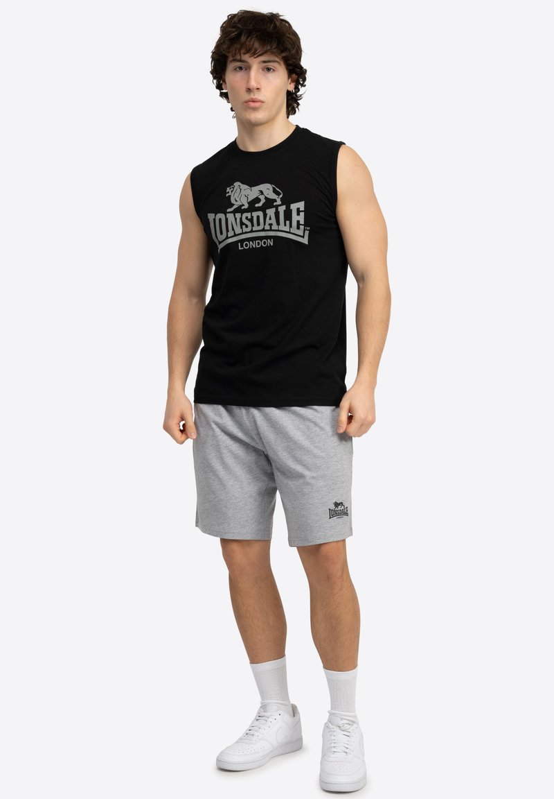 Juodas be rankovių marškinėliai su balta "Lonsdale London" grafika, derinami su pilkais šortais su logotipu, avimi baltais sportbačiais ir kulkšnies kojinėmis.
