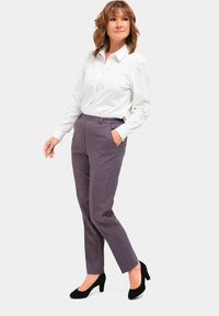 Elastische taillebroek in een gedempte paarse ruitpatroon, gecombineerd met een witte blouse met knopen. Zwarte hoge hakken. Eenvoudig en op maat gemaakt ontwerp.