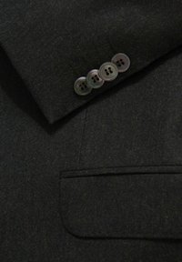Czarna wełniana marynarka o fakturowanym wykończeniu, z klapami w kształcie notch, kieszenią na piersi oraz czterema szarymi guzikami na mankietach.