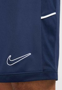 Marineblaue Nike-Shorts aus leichtem Material, mit einem weißen Logo und Kontrastnähten. Netzstruktur an den Seitenteilen.