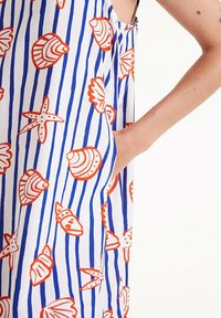 Abito senza maniche con uno sfondo bianco, righe verticali blu e motivi di conchiglie arancioni. Include una tasca laterale.