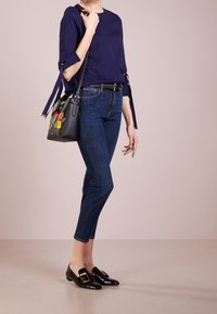 Námořnická blůza s jemným rukávem, tmavé džínové kalhoty, černá kožená taška s květinovou výšivkou a černé mokasíny se zlatým detailem na sponě.