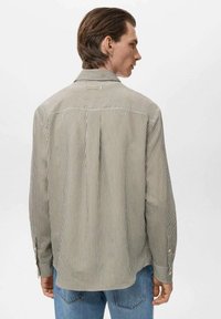 Camisa de manga larga a rayas en beige y verde oliva. Puños abotonados, pliegue en la parte posterior y detalle de yugo. Fabricada en tejido ligero. Corte casual.