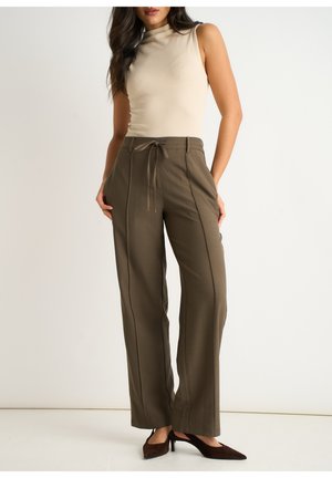 Beige sleeveless top paired with olive green wide-leg pants featuring a drawstring waist and contrasting side seams. Brown high-heeled shoes.