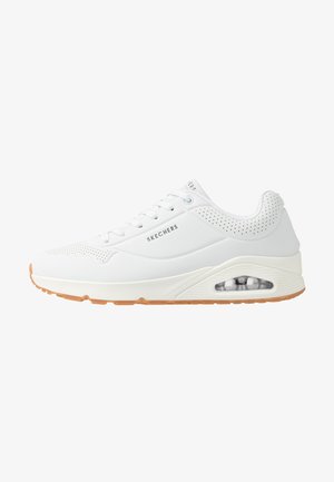 Witte sneaker met een gladde synthetische bovenkant, vetersluiting, geperforeerde accenten en een zichtbare luchtkusseneenheid in de zool. Rubberen outsole.