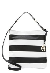 Sac d'épaule rayé large horizontal en noir et blanc avec deux bretelles et un pendentif logo rond en métal doré sur le côté.