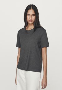 Maglietta in cotone grigio scuro con scollatura tonda e maniche corte. Il tessuto sembra morbido e ha una superficie liscia. Design semplice e senza fronzoli.