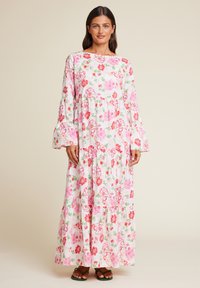 Blomstrende maxikjole i hvit med rosa og røde blomster, lange bell-ermer, lagdelt design, laget av lett materiale. Grønne sandaler inkludert.