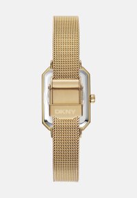 Orologio in acciaio inossidabile con rete dorata, quadrante ottagonale e dettagli argentati, con una chiusura contrassegnata con "DKNY". Design minimalista.