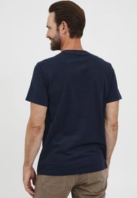 Mørkeblå kortærmet t-shirt i bomuld. Bagsiden har en rund halsudskæring og minimal syning, med en afslappet pasform.