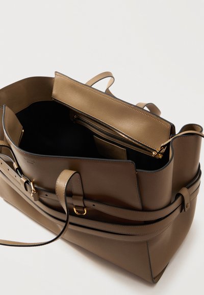 Sac cabas en cuir marron avec double poignée, ouverture sur le dessus montrant l'intérieur noir, poche intérieure zippée et sangle extérieure réglable avec ferrures dorées.