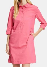 Abito rosa con bottoni, maniche a tre quarti, dotato di colletto, patta frontale e tasche laterali. Realizzato in tessuto leggero e morbido.