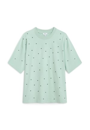 Mintgrünes T-Shirt mit kurzen Ärmeln und gleichmäßig verteilten schwarzen Polka-Dots auf der Vorderseite. Weicher Stoff, lockere Passform, runder Halsausschnitt.