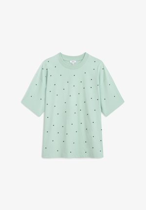 Mintgrünes T-Shirt mit kurzen Ärmeln und gleichmäßig verteilten schwarzen Polka-Dots auf der Vorderseite. Weicher Stoff, lockere Passform, runder Halsausschnitt.