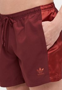 Bordo kupaći šorc s elastičnom talijom i vezicom, s sjajnim bočnim panelom i izvezenim logotipom na donjem dijelu nogavice.