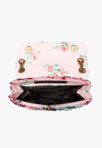 Sac à main en tissu rose à motif floral avec ferrures dorées, orné d'une bordure perlée. L'intérieur est doublé de noir et offre un grand espace de rangement.
