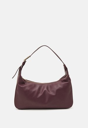 Dunkellila Lederschultertasche mit einem verstellbaren Riemen und einem goldenen Reißverschluss oben, vor einem schlichten Hintergrund.