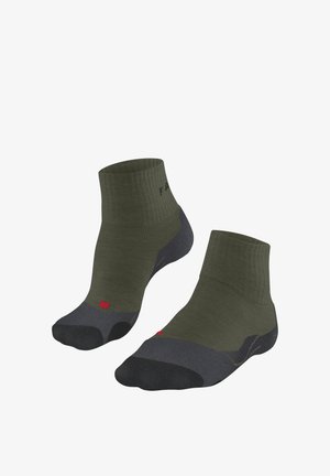 Enkelsokken in olijfgroen met een geribbelde structuur, donkergrijze accenten op de teen en hak, en een rood logodetail aan de zijkant.