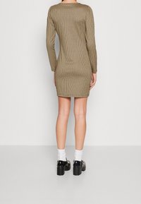 Robe ajustée à manches longues en motif à carreaux avec une palette de couleurs or et noir, dotée d'un col rond et d'un tissu extensible.