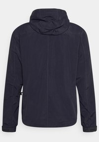 Chaqueta impermeable azul marino con capucha, con una textura suave, puños elásticos y bolsillos laterales, diseñada para uso al aire libre.